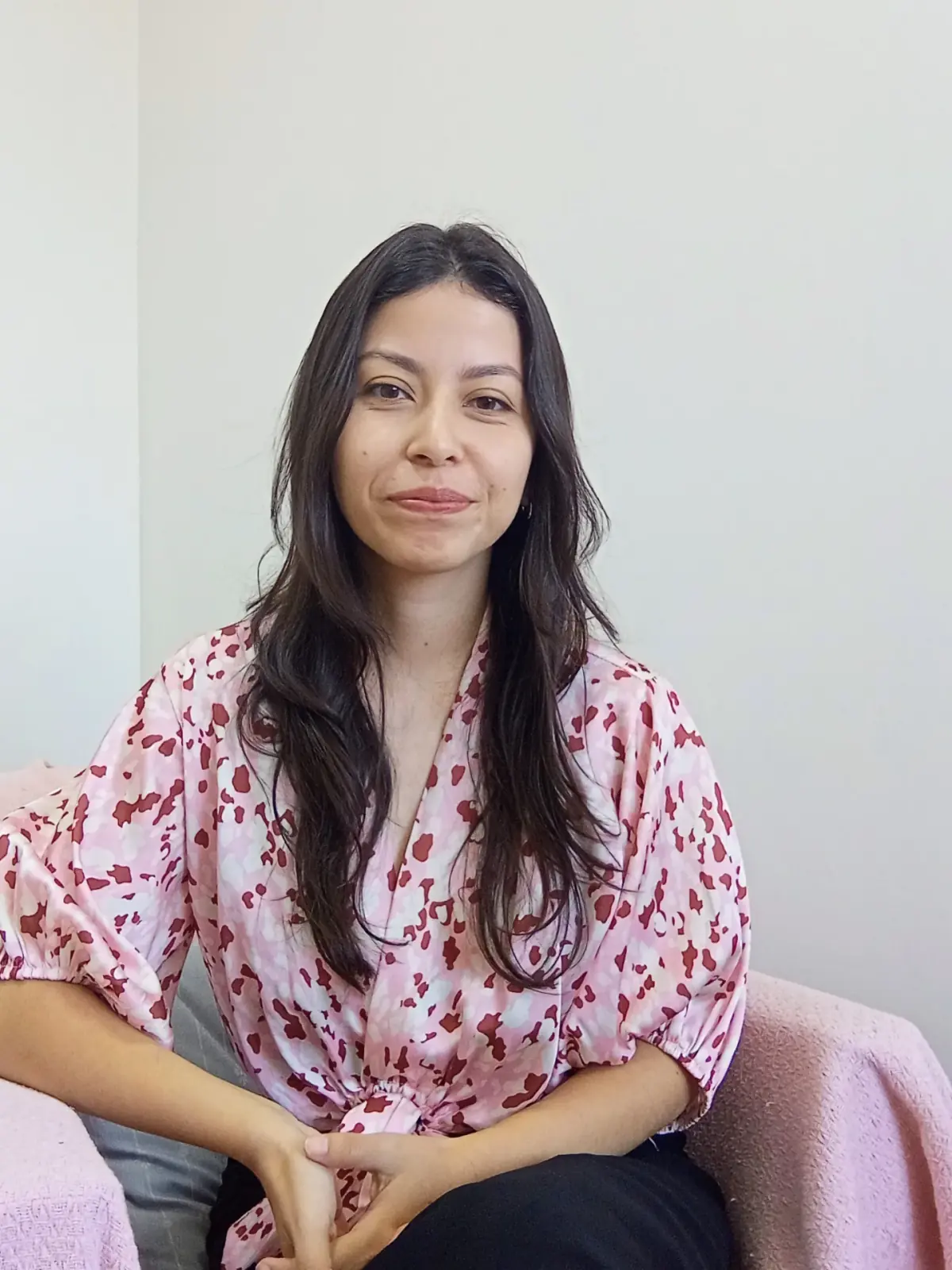 Foto da terapeuta no seu consultório real, com postura acolhedora e sóbria
